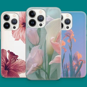 Può includere: Tre custodie per telefono con disegni floreali. Una custodia presenta un fiore di ibisco, un'altra mostra fiori rosa e bianchi e la terza mostra iris contro un cielo blu. Le custodie hanno una finitura lucida e sono progettate per uno smartphone.