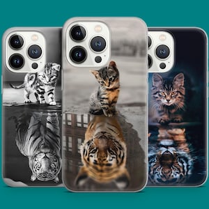 Può includere: Tre custodie per telefono con immagini di gattini e tigri. Le custodie presentano un bordo trasparente e raffigurano un gattino sopra un riflesso di tigre. Le custodie hanno sfondi diversi, tra cui bianco e nero e un paesaggio urbano sfocato.
