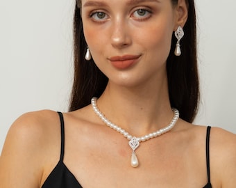 May include: A pearl necklace and matching earrings set. The necklace features a strand of white pearls with a diamond-like pendant and a single teardrop pearl. The earrings have a similar design, with a diamond-like top and a teardrop pearl.