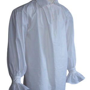 May include: A white long-sleeved shirt featuring a classic collar, a front placket, and gathered fabric at the shoulders. The sleeves are voluminous and end in fitted cuffs with flared, ruffled edges that extend past the wrist area.