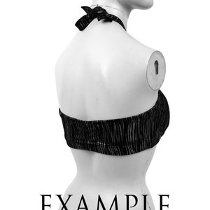 May include: Black halter top with vertical textured stripes. The top is tied at the neck with a bow. The word "EXAMPLE" is printed in black at the bottom of the image.