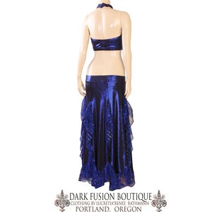 May include: A two-piece dance costume in a deep blue colour. The halter top and skirt are made of a shiny fabric, with the skirt featuring layered ruffles and decorative accents. The costume is displayed on a mannequin.