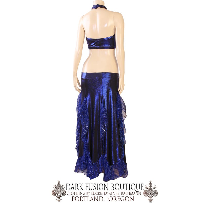 May include: A two-piece dance costume in a deep blue colour. The halter top and skirt are made of a shiny fabric, with the skirt featuring layered ruffles and decorative accents. The costume is displayed on a mannequin.