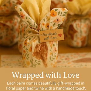 May include: A small item wrapped in cream-colored paper featuring a yellow and orange floral pattern, tied with brown twine. A rectangular tan tag attached to the twine displays the text Handmade with Love and a small red heart icon.