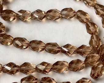 May include: A strand of brown faceted glass beads. The beads are oval shaped and have a shiny finish.