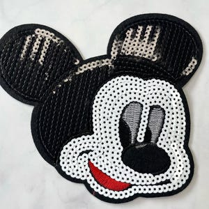 May include: Black and white sequined Mickey Mouse character patch with red embroidered smile.