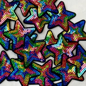 May include: A group of colorful star-shaped patches made of iridescent sequins. The patches are arranged in a random pattern and are all the same size.