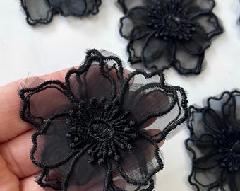 May include: Black sheer fabric flower appliques with a delicate lace trim. These floral embellishments are perfect for adding a touch of elegance to clothing, accessories, or home decor projects.