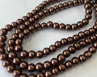 May include: A strand of brown pearl beads. The beads are round and have a smooth, glossy finish.