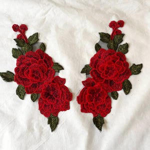 Puede incluir: Dos parches bordados con vibrantes rosas rojas con hojas y tallos verdes. Los diseños florales están detallados con costuras intrincadas, perfectos para agregar un toque decorativo a la ropa o los accesorios.