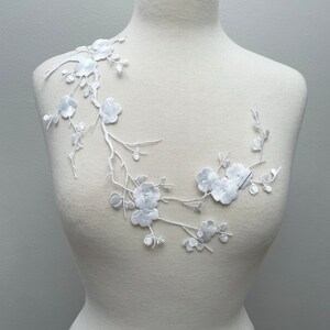 Puede incluir: Aplique floral bordado blanco con delicadas ramas y flores. Este diseño es perfecto para agregar un toque de elegancia a la ropa, los accesorios o los proyectos de decoración del hogar.