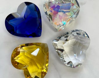 May include: Four crystal heart-shaped prisms in different colors: blue, iridescent, clear, and yellow.