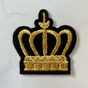 May include: A gold embroidered crown patch on a black felt background. The crown has five points and a rounded top.
