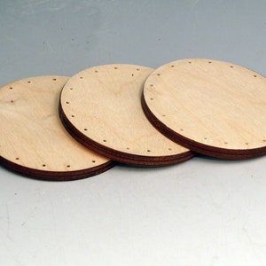 May include: Three round wooden bases with holes around the edges. The bases are stacked on top of each other.