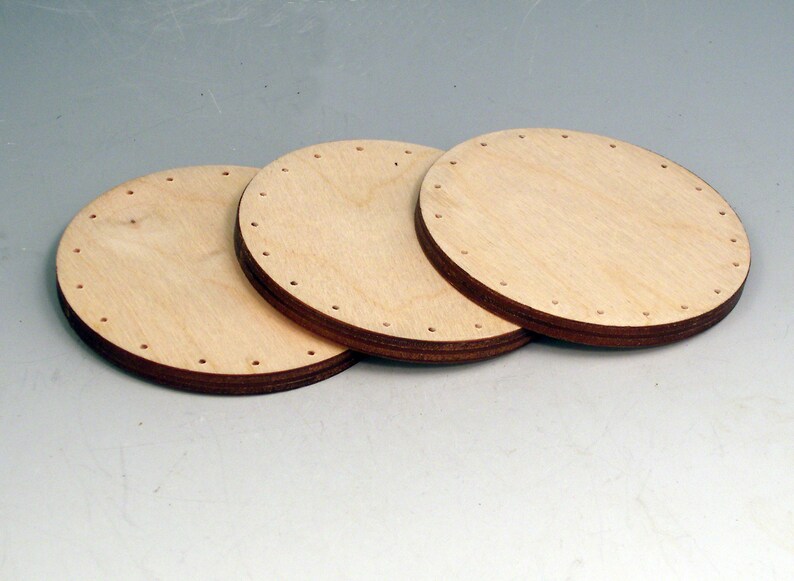 May include: Three round wooden bases with holes around the edges. The bases are stacked on top of each other.