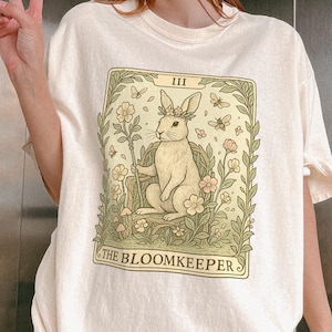 T-shirt couleurs confort Tarot The Bloomkeeper, chemise carte Bunny Oracle, t-shirt floral sorcière, vêtements en noyau forestier pastel, t-shirt magie de la nature