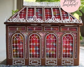Puede incluir: Una casa de pan de jengibre construida como un invernadero victoriano, con paredes de pan de jengibre marrón, detalles de glaseado blanco y ventanas translúcidas rojas y naranjas. Una etiqueta circular rosa dice Recipes Included!