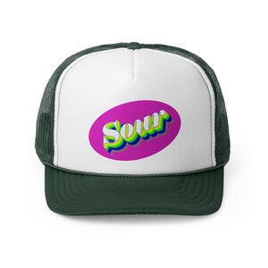 Może przedstawiać: Biała i zielona czapka trucker z różowym owalnym naszywką, na której napisano "Sour" retro czcionką.