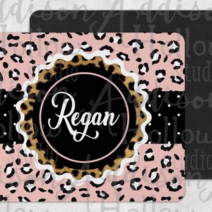 May include: A pink and brown leopard print mouse pad with a white scalloped circle in the center. The circle has a black background and the name "Regan" written in white cursive.