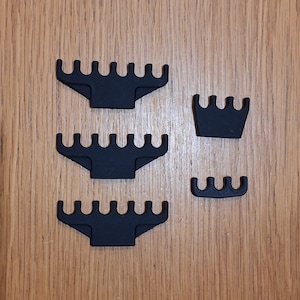 May include: Three black plastic wire loom clips with six slots and one black plastic wire loom clip with four slots.