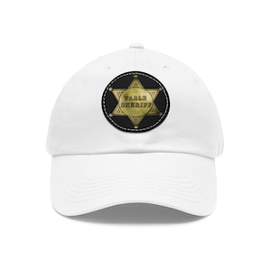 Puede incluir: Gorra de béisbol blanca con un parche negro con un diseño de insignia de sheriff dorada. La insignia tiene las palabras "TABLE SHERIFF" en letras doradas. La gorra está hecha de un material suave y duradero.