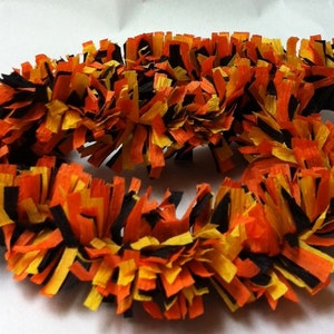 May include: Black, orange, and yellow paper streamer garland. The streamer is curled and twisted to create a festive look.