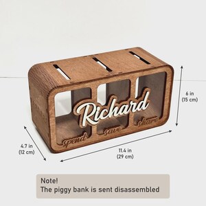 May include: A rectangular wooden piggy bank with three compartments labelled spend, save, and share. The name Richard is in white script on the front. It measures 29 cm long, 12 cm deep, and 15 cm high. Note: The piggy bank is sent disassembled.