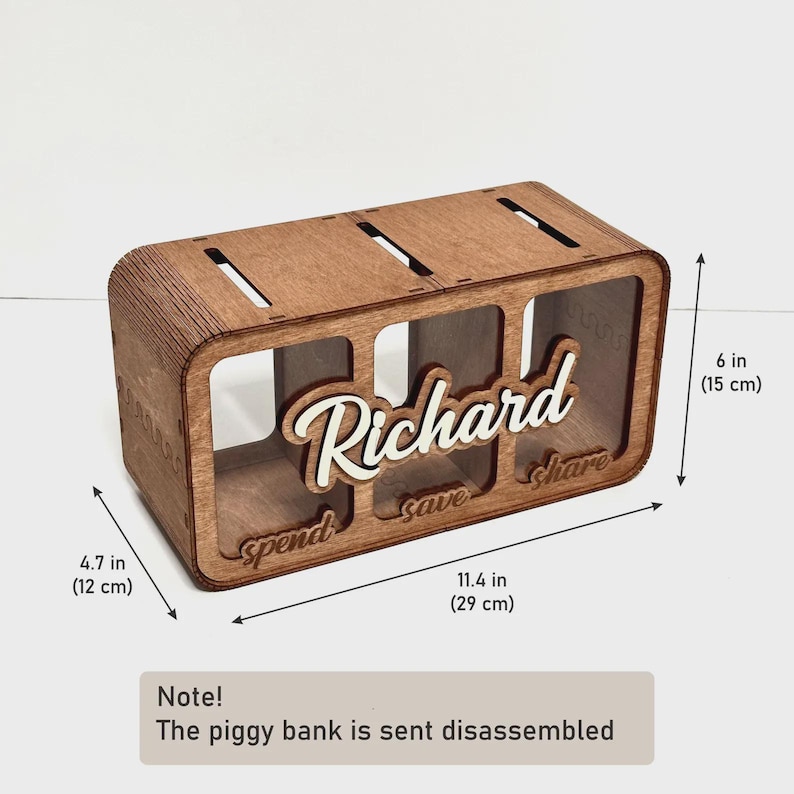 May include: A rectangular wooden piggy bank with three compartments labelled spend, save, and share. The name Richard is in white script on the front. It measures 29 cm long, 12 cm deep, and 15 cm high. Note: The piggy bank is sent disassembled.