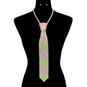 May include: A pink and green beaded tie necklace with matching stud earrings. The tie is made of small beads in alternating rows of pink and light green. The necklace and earrings are displayed on a black mannequin.