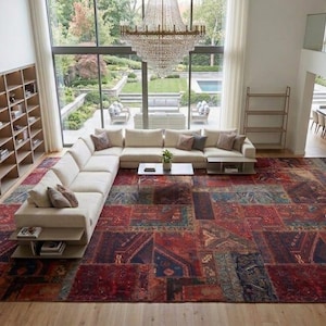 Könnte beinhalten: Ein großer, rechteckiger Teppich mit Patchwork-Design in tiefem Rot, Marineblau und gedeckten Erdtönen. Der Teppich zeigt ein komplexes, abgenutztes Muster aus geometrischen und floralen Motiven und bedeckt einen Großteil des Wohnzimmerbodens.