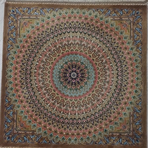 Puede incluir: Alfombra cuadrada con un intrincado diseño de medallón central. La alfombra presenta un borde y flecos marrones, con un detallado patrón floral en tonos rosas, azules y dorados. El diseño central es circular.