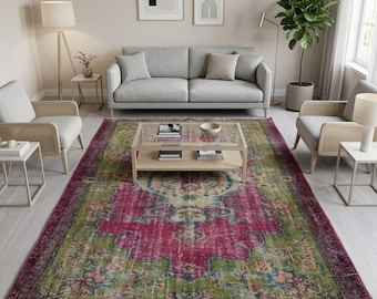 May include: A rectangular area rug featuring a distressed pattern with a prominent magenta center medallion, olive green borders, and intricate floral motifs in shades of teal, cream, and orange, covering the floor in a living room setting.