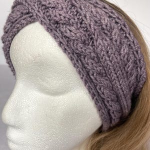 May include: A purple knitted headband with a cable knit pattern.