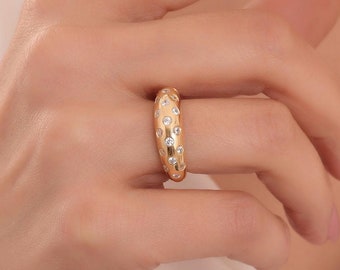 Può includere: Un anello d'oro con una fascia testurizzata e piccole pietre chiare incastonate nella fascia.