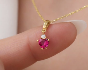 May include: A gold necklace with a small heart-shaped pendant featuring a pink gemstone and a single clear diamond.