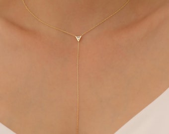 May include: A gold chain necklace with a small triangle pendant and a square pendant at the end. Both pendants have a clear stone in the center.