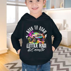 May include: A black hooded sweatshirt with a colorful graphic of a monster truck. The graphic says "Born to Roam" and "Little Rad Dirt Monster".