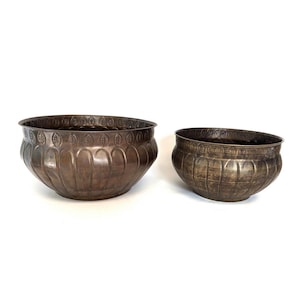 May include: Two antique-style metal bowls with a decorative leaf pattern around the rim. The bowls are brown and have a slightly distressed finish.