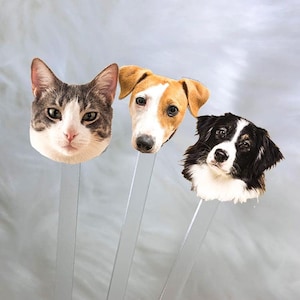 May include: Three clear acrylic sticks with animal faces printed on the top. The faces are a cat, a brown and white dog, and a black and white dog.