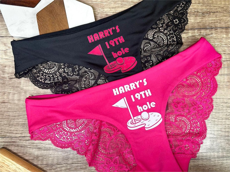 May include: Two pairs of black and pink lace underwear with the text "HARRY'S 19TH HOLE" and a golf ball graphic.