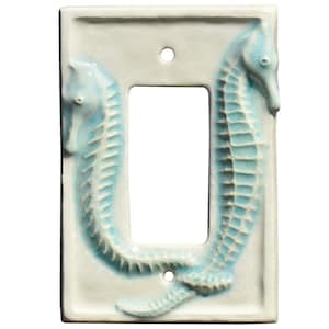 Puede incluir: Una placa de cerámica para interruptor de luz con forma rectangular y una abertura central. Dos figuras de caballitos de mar turquesa están esculpidas a ambos lados de la abertura, sobre un fondo blanco. Los caballitos de mar tienen detalles.