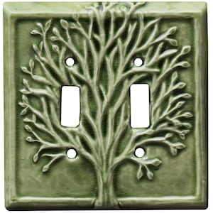 May include: A green ceramic light switch cover with a raised design of a tree with branches and leaves.