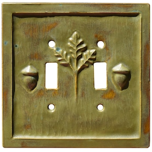 以下が含まれることがあります： オークの葉とドングリがエンボス加工された緑色のセラミック製ライトスイッチカバーです。