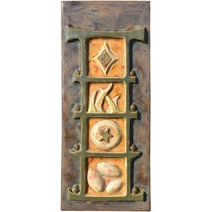 Puede incluir: Una baldosa cerámica rectangular con un fondo texturizado, moteado azul y marrón. La baldosa presenta un diseño de cuadrícula con cuatro cuadrados naranjas, cada uno con un diseño en relieve diferente: un diamante, llamas, una estrella y tres óvalos.