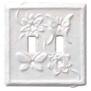 May include: White ceramic double light switch cover with embossed floral and butterfly designs. The cover features two switch openings and a raised border. The decorative design includes two flowers and two butterflies.