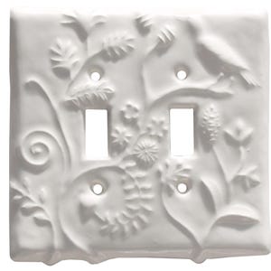Op de afbeelding: Witte keramische dubbele lichtschakelaar cover met een reliëf ontwerp van een vogel, bloemen en bladeren. De cover heeft twee schakelaar openingen en drie schroefgaten. Het ontwerp is gedetailleerd en gestructureerd.