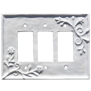 Puede incluir: Cubierta de interruptor de luz triple blanca con dise&ntilde;o floral y de vid en relieve. La cubierta tiene tres aberturas rectangulares para los interruptores. Los elementos decorativos est&aacute;n en las esquinas y los lados.