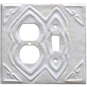 May include: White ceramic outlet and light switch cover with an intricate, embossed design. The cover has a raised, geometric pattern around the edges.