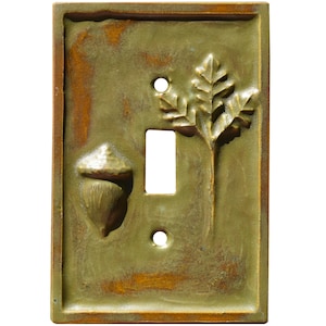 Puede incluir: Una tapa de interruptor de luz de cer&aacute;mica con un dise&ntilde;o de bellota y hoja de roble. La tapa es verde con acentos marrones.