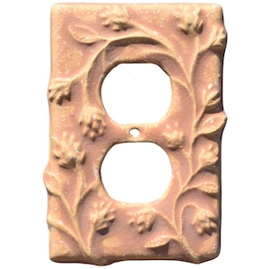 以下が含まれることがあります： 桃色の装飾的な電気コンセントカバー。カバーにはコンセント用の2つの円形の開口部があり、エンボス加工された葉と花で飾られており、自然にインスパイアされたエレガンスをあらゆる部屋に追加します。